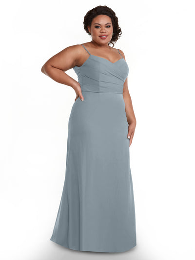 A woman poses with one hand on her hip in the Avery Austin 80169, a floor-length, light blue chiffon dress featuring thin straps and a fitted, pleated bodice, set against a plain white background.