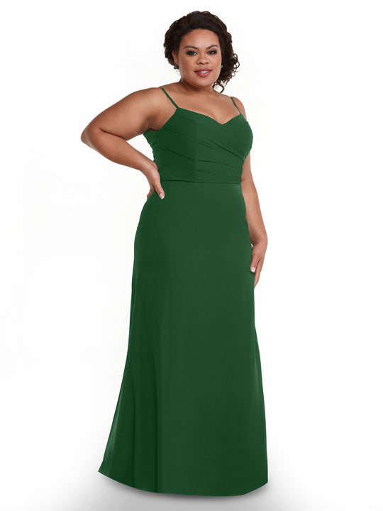 A woman confidently poses with one hand on her hip, smiling in the Avery Austin TH-80169 sleeveless, floor-length dark green chiffon dress featuring a pleated bodice, set against a plain white background.