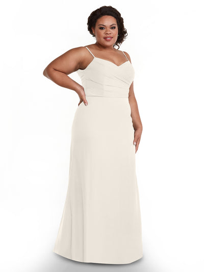 A woman with dark curly hair is smiling with one hand on her hip, wearing Avery Austin's floor-length chiffon dress (Style 80169) featuring a sleeveless design, pleated bodice, and V-neckline against a plain white background.