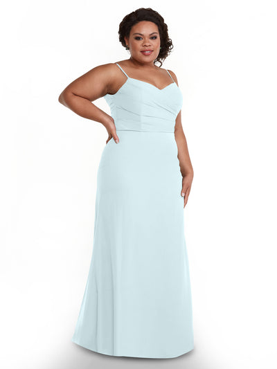 A woman wears the Avery Austin 80169—a light blue chiffon dress with a pleated bodice and thin straps—standing confidently against a white background, smiling with one hand on her hip.