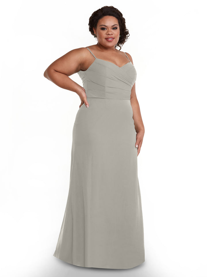A woman wearing Avery Austin’s 80169—a light gray, floor-length chiffon dress with a pleated bodice and sweetheart neckline—poses against a white background, smiling slightly with one hand on her hip.