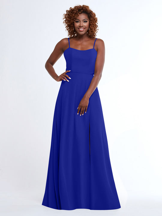 A woman with curly hair wears the Avery Austin 80170, a sleeveless royal blue A-line dress with spaghetti straps and side slit, smiling against a plain white background.
