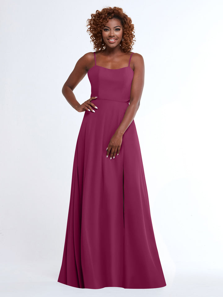 A woman with curly hair smiles in the Avery Austin 80170, a flowy magenta A-line dress with spaghetti straps, against a plain white background.