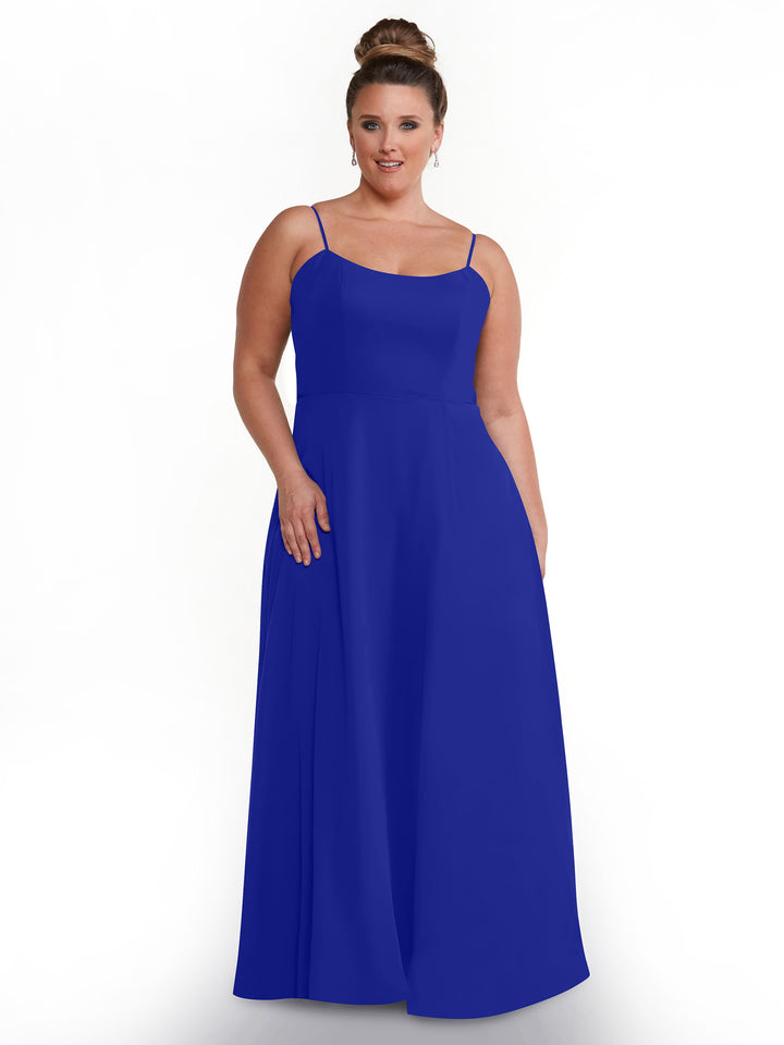 A woman with light skin and brown hair in a bun models the Avery Austin 80170, a sleeveless, floor-length royal blue dress with spaghetti straps, standing against a plain white background.