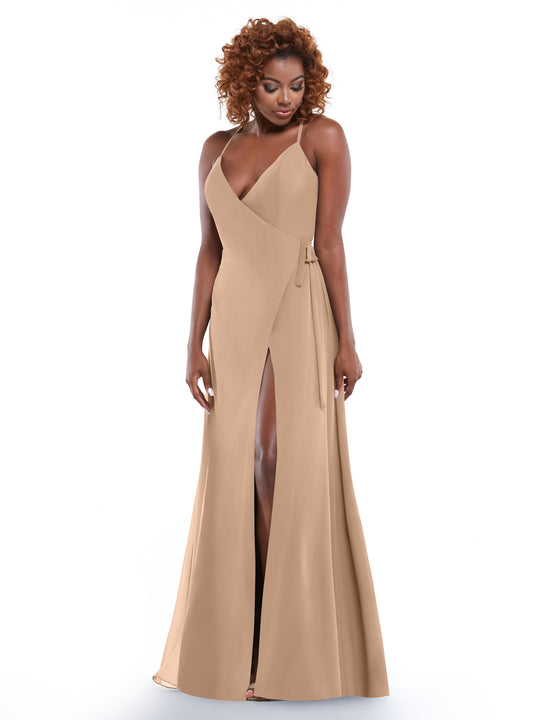 A woman with curly hair models Avery Austin’s 80171—a sleeveless beige floor-length wrap dress featuring a deep V-neckline, self-tie sash, and slit—standing against a plain white background.