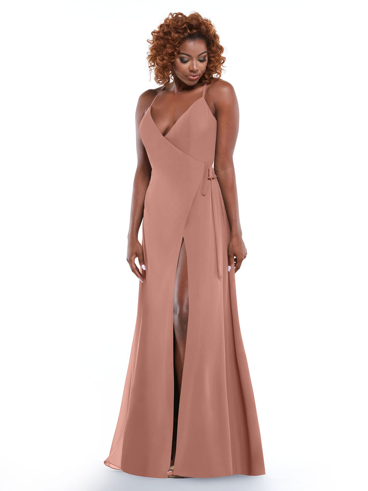 A woman with curly hair wears Avery Austin’s 80171, a rose sheath dress with a deep V-neck, high front slit, and self-tie sash, standing against a white background.