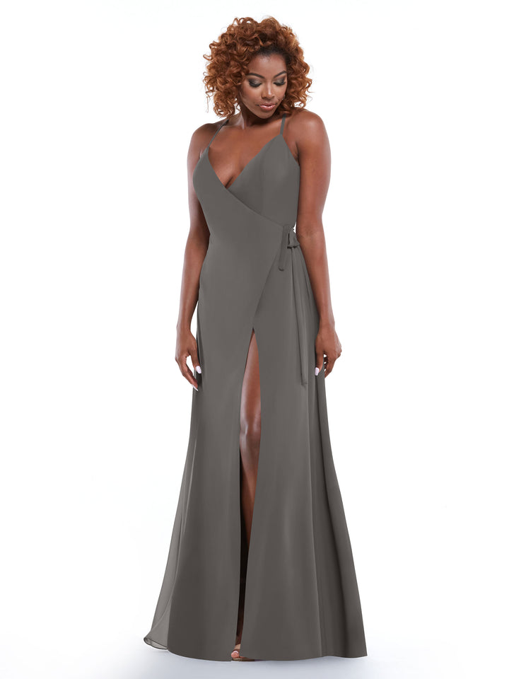 A woman with curly hair models the Avery Austin 80171, a sleeveless slate gray floor-length dress with a V-neckline and high slit, standing against a white background.