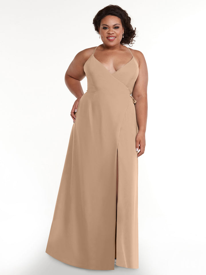 A woman smiles at the camera in the Avery Austin 80171 sleeveless beige wrap slit dress, featuring a deep V-neckline and self-tie sash, against a plain white background.