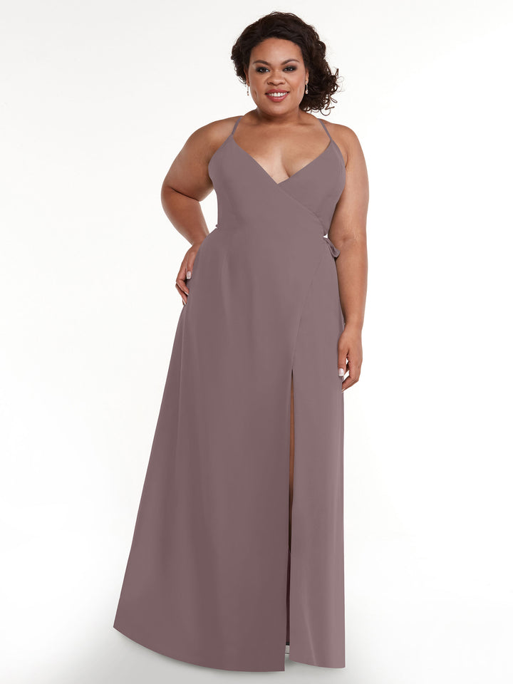 A woman smiles against a white background wearing the Avery Austin 80171: a sleeveless, mauve V-neck dress with a self-tie sash and thigh-high slit.
