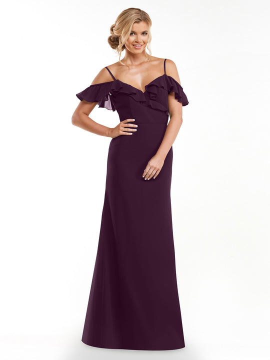 A woman in the Avery Austin 80172, a long deep purple A-line dress with ruffled neckline and off-the-shoulder sleeves, smiles with one hand on her hip against a plain white background.