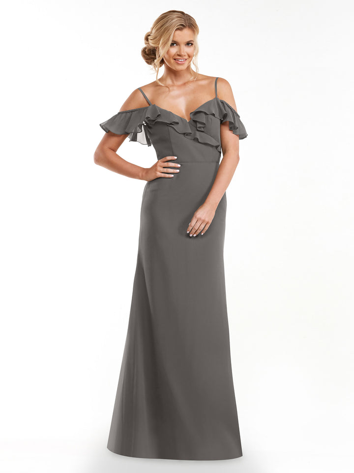 A woman models the Avery Austin 80172 slate gray A-line dress with off-the-shoulder sleeves and a ruffled neckline, standing against a white background and smiling with one hand on her hip.