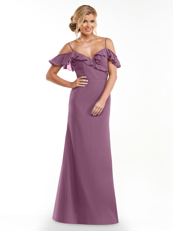 A woman stands confidently with one hand on her hip against a white background, wearing Avery Austin’s 80172: a floor-length mauve A-line dress featuring an off-the-shoulder ruffled neckline and thin straps.
