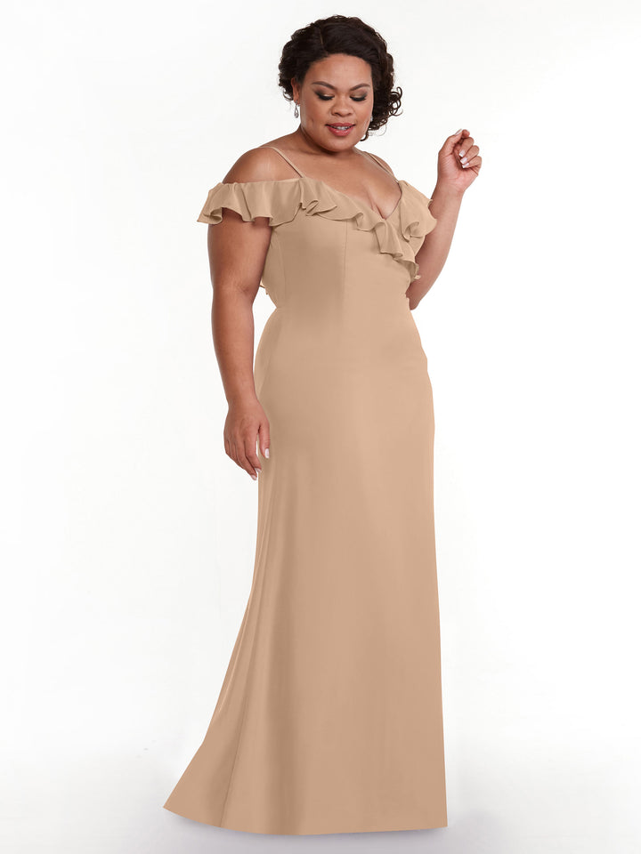 A woman models Avery Austin’s 80172, an off-the-shoulder, floor-length beige A-line dress with a ruffled neckline, standing against a plain white background.