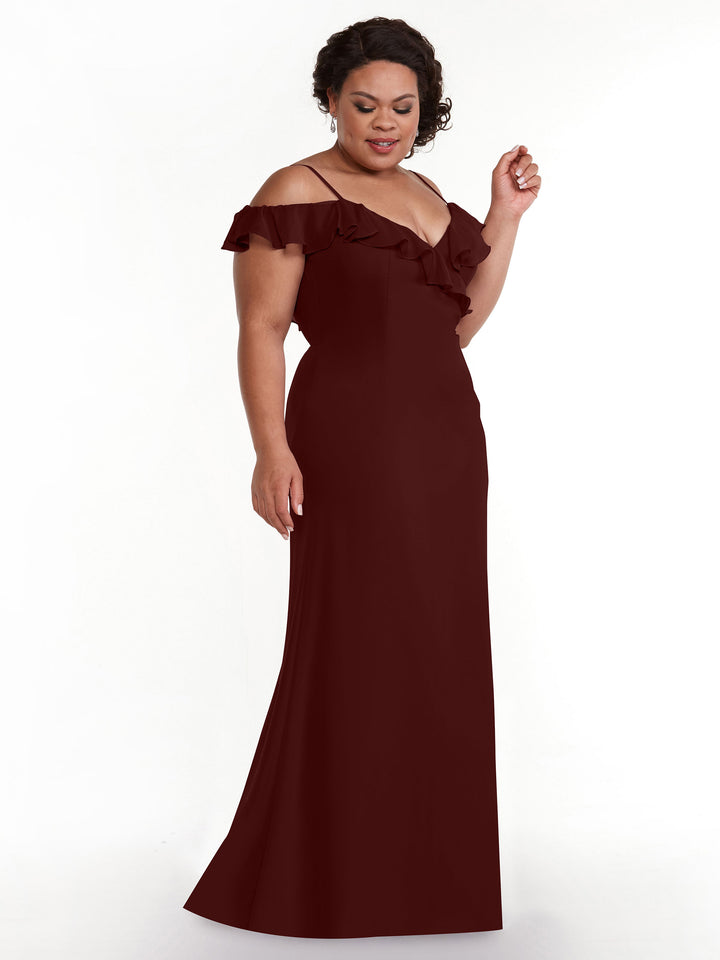 A woman models the Avery Austin 80172, a floor-length A-line burgundy gown with off-the-shoulder sleeves and ruffled details, standing against a plain white background.