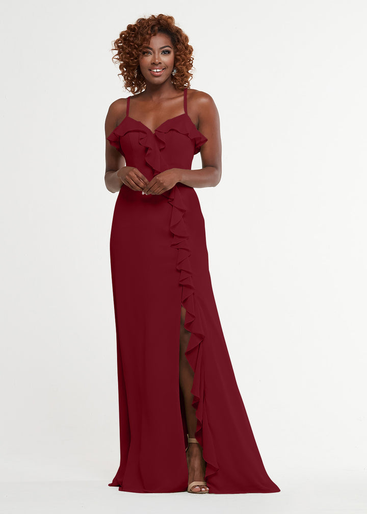 A woman with curly hair models Avery Austin’s 80174: a floor-length, sleeveless burgundy ruffled dress with a thigh-high slit and sweetheart bodice, standing against a plain white background.