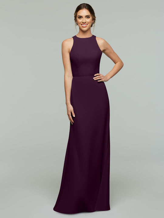 A woman smiles in Avery Austin’s 80175 dress, a sleeveless, floor-length A-line with a fitted bodice and high neckline in aubergine, posing against a plain light gray background.