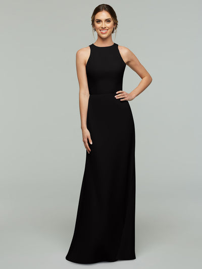 A woman poses with a smile in Avery Austin style 80175, a sleeveless floor-length black A-line dress featuring a high neckline and keyhole back, her hair styled back, one hand on her hip against a light gray background.