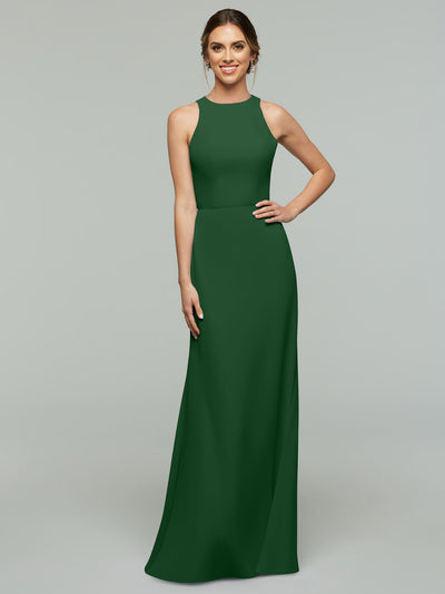 A woman in the Avery Austin 80175 sleeveless, emerald green V-neck A-line gown stands against a plain light gray background, smiling with one hand on her hip.
