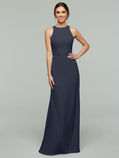 A woman smiles in Avery Austin’s 80175 dress—an elegant, long navy A-line with a fitted waist, high neckline, and subtle keyhole back—set against a plain light gray background.