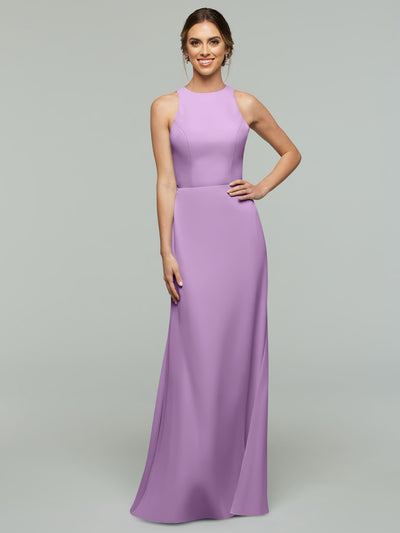 A woman smiles in Avery Austin’s 80175, a sleeveless floor-length lavender A-line dress with a fitted bodice, V-neck, and flowing skirt, set against a plain light gray background.