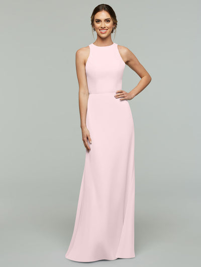 A woman poses with a smile, wearing Avery Austin's 80175—a sleeveless, floor-length light pink A-line dress with a fitted bodice and flowing skirt—her hand on her hip against a plain light gray background.