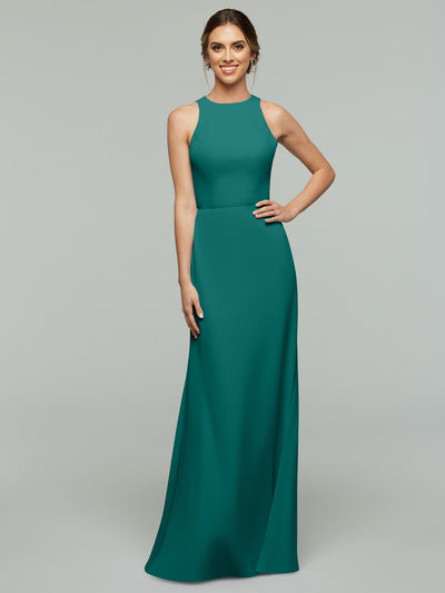 A woman smiles in Avery Austin’s 80175, a sleeveless floor-length A-Line dress with a high neckline. Her hair is styled back as she poses with one hand on her hip against a plain light gray background.