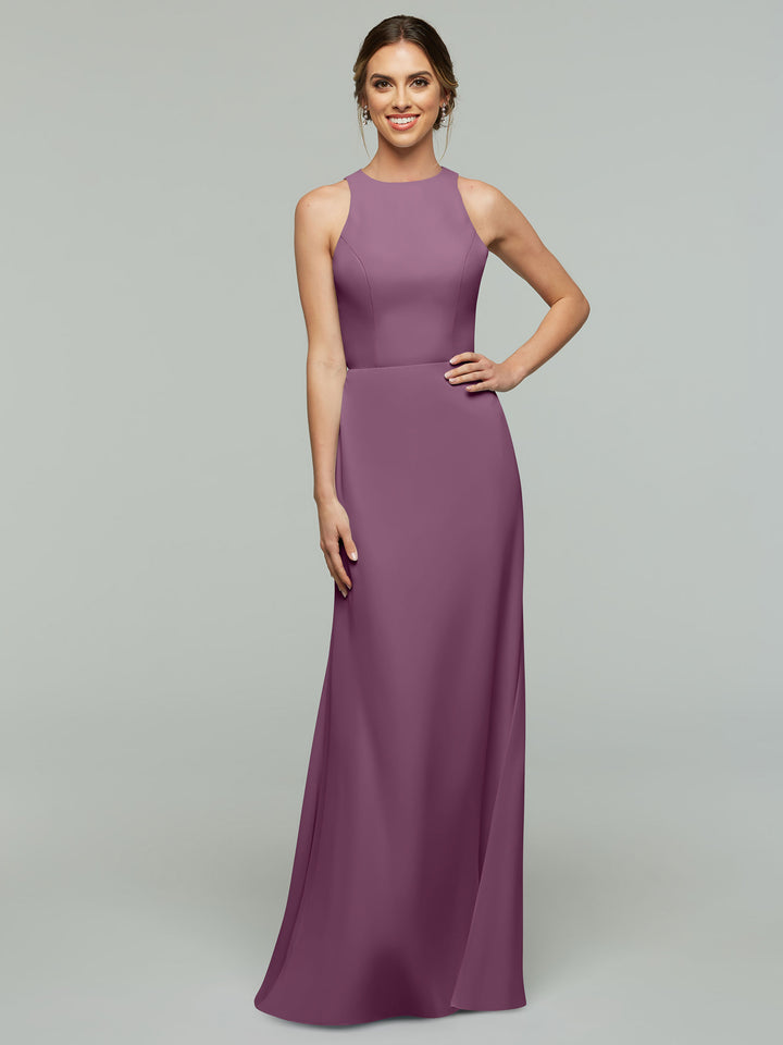 A woman stands smiling with one hand on her hip, modeling Avery Austin’s sleeveless, floor-length mauve A-Line dress (Style 80175) with a high neckline against a plain gray background.