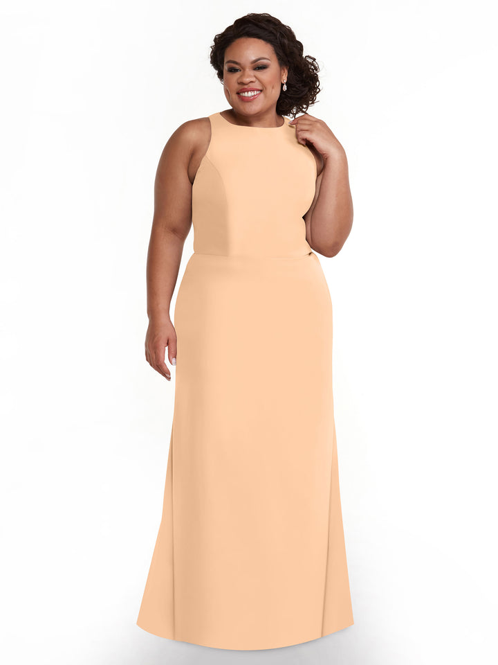A woman in the Avery Austin 80175 blush sleeveless A-line floor-length V-neck dress stands against a white background, smiling with one hand touching her hair.