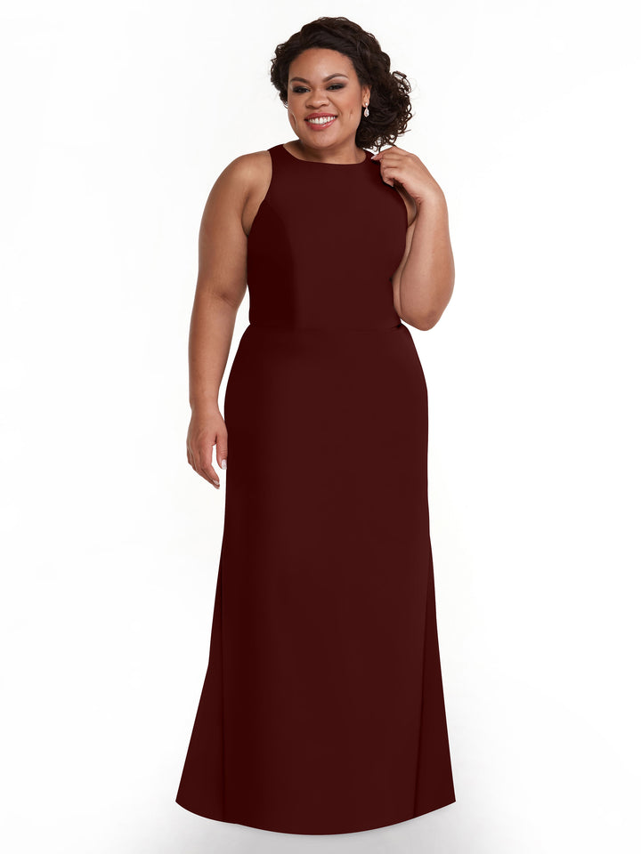 A woman with curly hair styled up wears drop earrings and smiles against a white background in Avery Austin’s sleeveless, floor-length A-Line dress (80175) in merlot, featuring a V-neck.