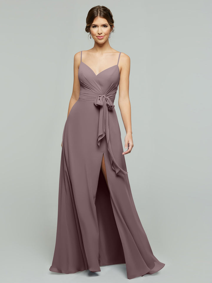 A woman models the averyaustin TH-80182 mauve A-line chiffon dress featuring thin straps, a V-neckline, ruched bodice, tied waist detail, and a front thigh-high slit against a plain light gray background.