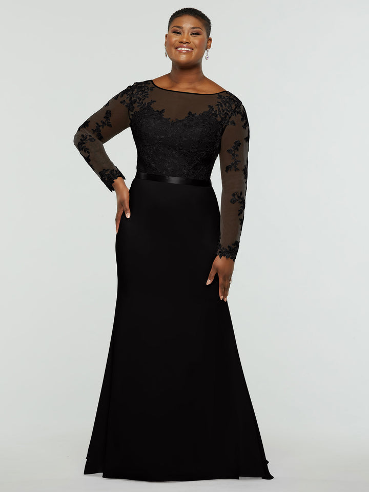 A woman smiles while wearing the averyaustin 80190 black chiffon mermaid dress, featuring an intricate lace bodice and illusion lace sleeves, against a plain light gray background.
