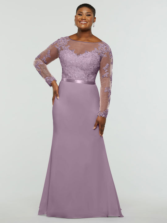 A woman wearing the averyaustin 80190—an elegant long lavender chiffon mermaid dress with a lace bodice and sheer long sleeves—stands smiling with one hand on her hip against a plain light background.