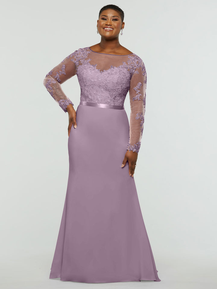 A woman wearing the averyaustin 80190—an elegant long lavender chiffon mermaid dress with a lace bodice and sheer long sleeves—stands smiling with one hand on her hip against a plain light background.