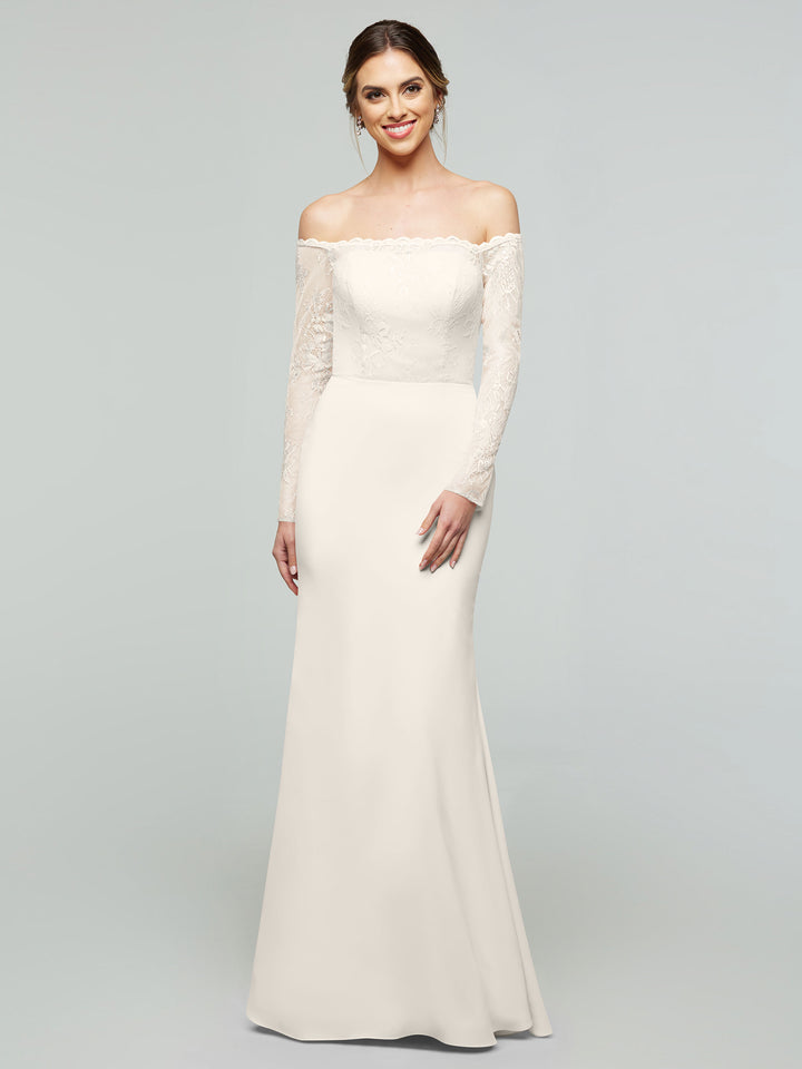 A woman smiles gently while wearing the averyaustin 80191 ivory chiffon off-the-shoulder mermaid dress with lace details on the bodice and sleeves, standing against a plain light gray background.