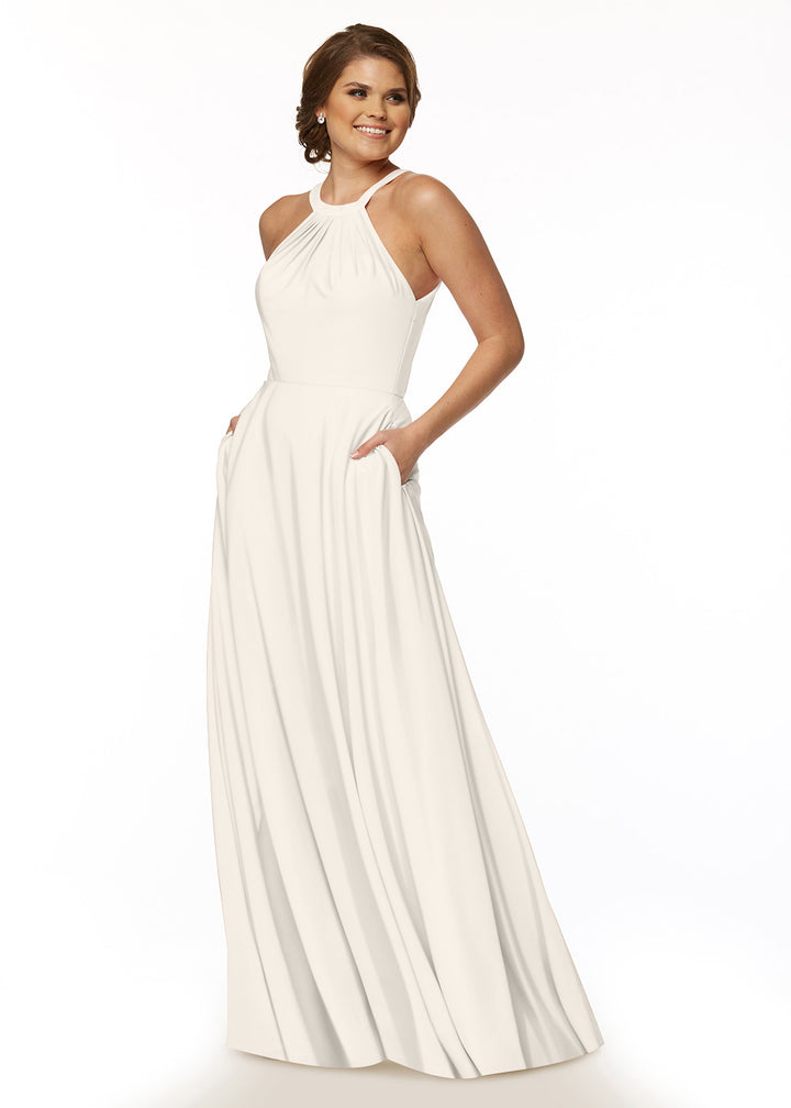 A woman smiles in the Avery Austin 83002, a sleeveless, floor-length A-line dress with a gathered halter neck and pockets. Its flowy skirt creates an elegant look against a plain white background.