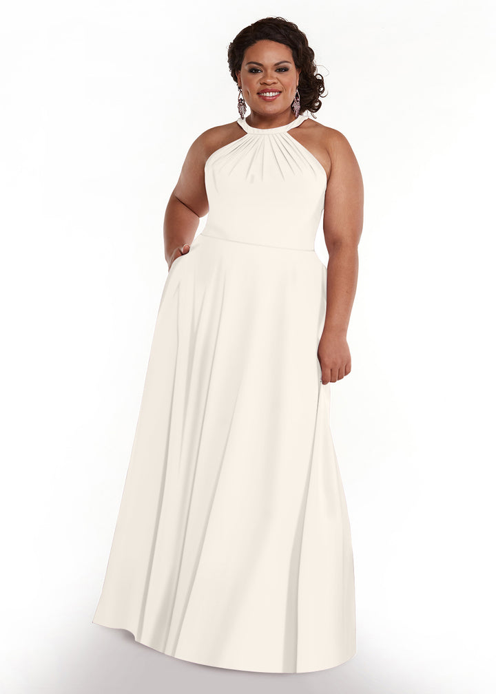 A woman with curly dark hair in an updo wears the Avery Austin 83002, an ivory A-line, floor-length halter neck dress with a gathered neckline, standing and smiling against a plain white background.
