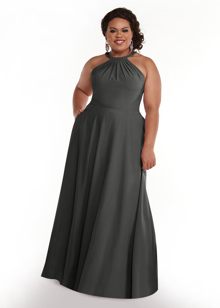 A woman wearing the Avery Austin 83002 gown in Steel Gray, featuring a halter neck with pleated neckline and flowy floor-length skirt, smiles against a plain white background.