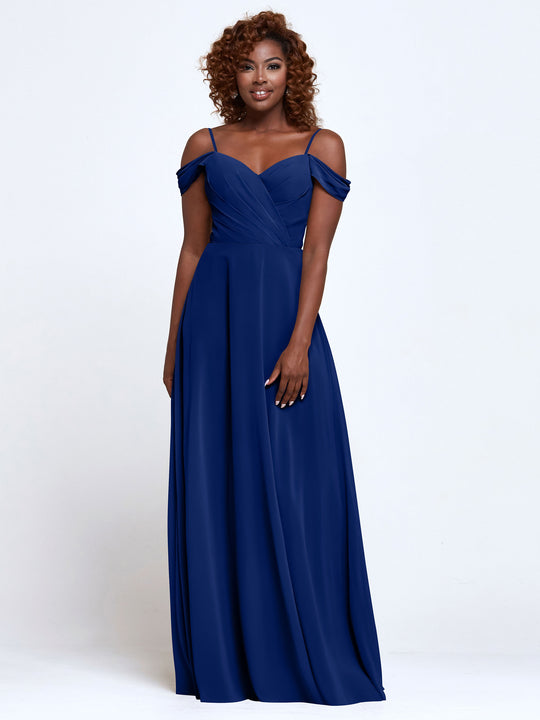 A woman with curly hair models Avery Austin's 83003—a royal blue, floor-length bridesmaid dress with thin straps, fitted bodice, and off-the-shoulder design—against a white background.