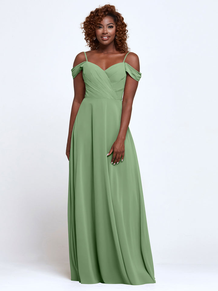 A woman smiles in Avery Austin’s 83003, a light green, off-the-shoulder bridesmaid dress with a ruched bodice and floor-length chiffon skirt. Her curly hair frames her face against a plain white background.