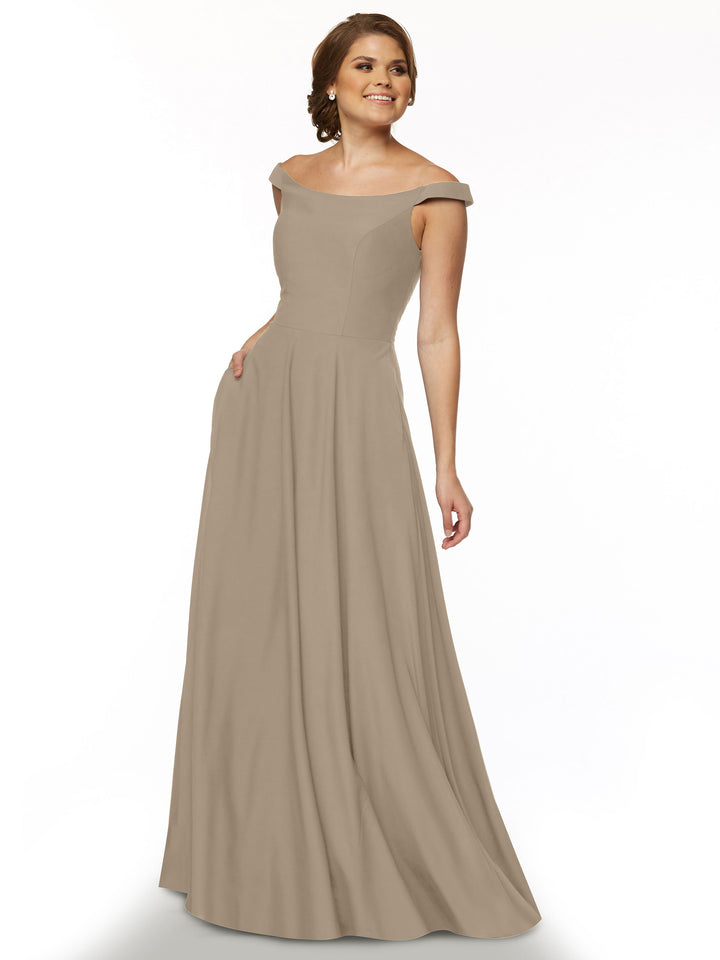 Model wearing Avery Austin 83005, a taupe off-the-shoulder floor-length dress with a fitted bodice and flared skirt, smiling against a white background.