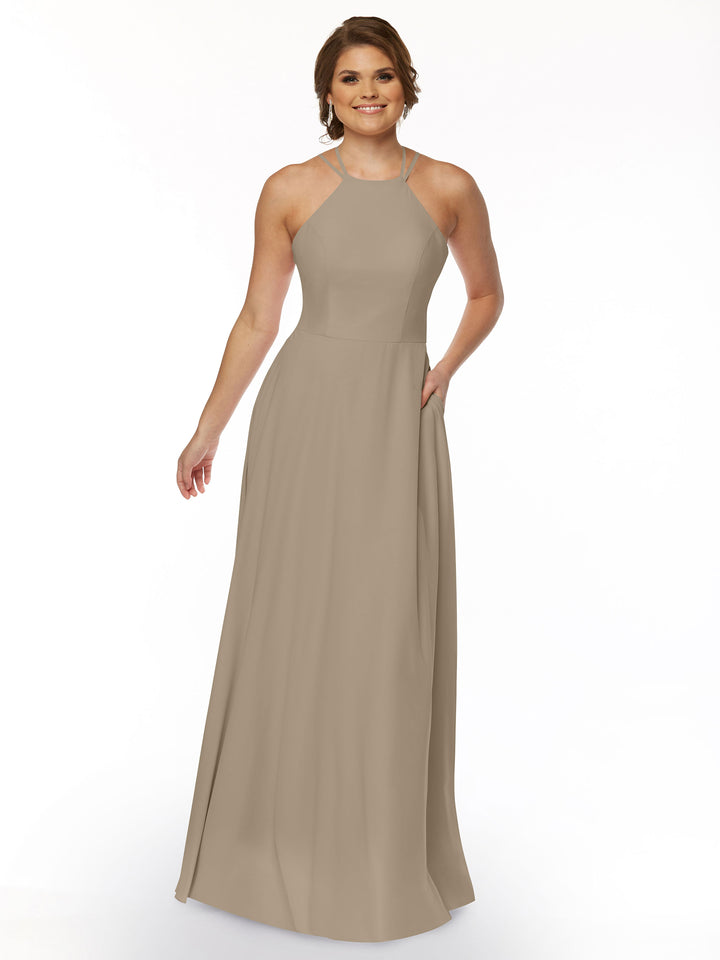 A woman poses against a plain white background wearing Avery Austin’s 83006, a sleeveless taupe A-line dress featuring a high halter neckline and subtle floor-length pleats.