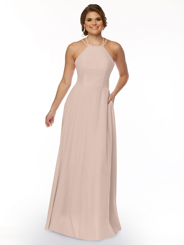 A woman with short brown hair smiles against a white background, holding one side of her Avery Austin TH-83006 A-Line dress, featuring a long silhouette in light pink and a halter neckline.