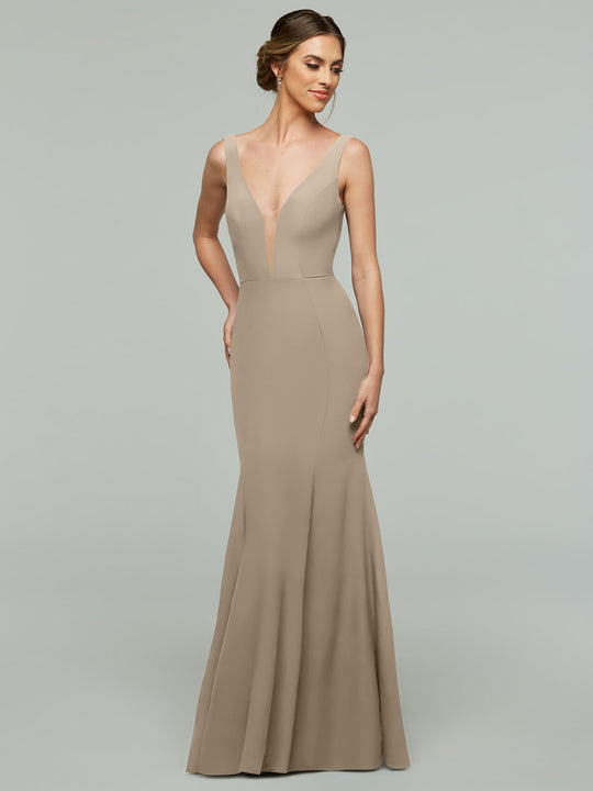 A woman poses against a light gray background wearing Avery Austin's 83010—a latte-colored, floor-length mermaid dress with a plunging neckline and fitted bodice.