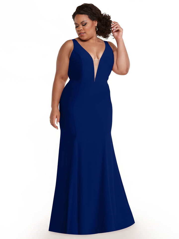 A woman poses against a white background, looking to the side and adjusting her hair in the Avery Austin 83010 sleeveless mermaid dress, featuring a cobalt color and plunging V-neckline.