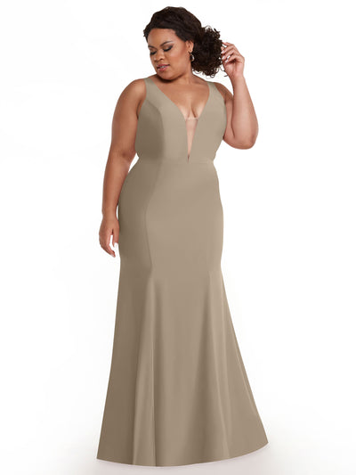 A woman poses with one hand in her hair against a white background, wearing Avery Austin’s 83010: a sleeveless, floor-length latte mermaid dress with a plunging neckline and fitted bodice.
