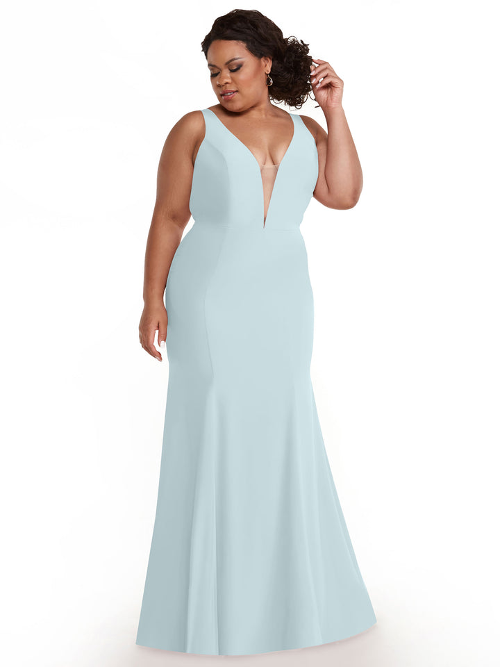 A woman in the Avery Austin 83010, an elegant light blue mermaid dress with a plunging neckline, stands against a white background, looking down and touching her hair.