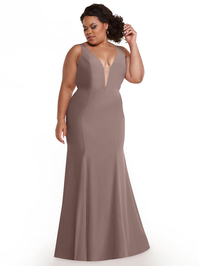 A woman in the Avery Austin 83010 dress, a vintage mauve, sleeveless, floor-length mermaid gown with a plunging neckline and fitted silhouette, stands against a white background, looking to the side while touching her hair.