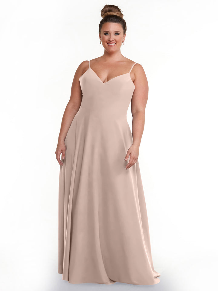 A woman with an updo hairstyle wears Avery Austin’s sleeveless, rose pink A-Line dress (style 83012) with a fitted bodice and flared skirt, standing and smiling against a plain white background.