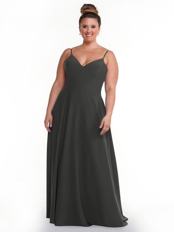 A woman smiles in the Avery Austin 83012, a sleeveless steel gray A-Line dress with spaghetti straps and a V-neckline. Against a white background, she wears her hair in an updo.