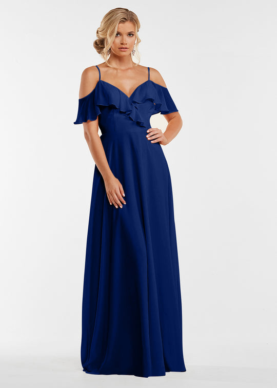 A woman with loose, wavy blonde hair models Avery Austin's floor-length royal blue dress (style 83013) featuring off-the-shoulder sleeves, spaghetti straps, and a ruffled neckline against a plain white background.